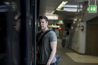Portrait of young man entering in train at railroad station