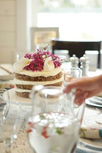 Cropped image of person holding jug against pancake on table