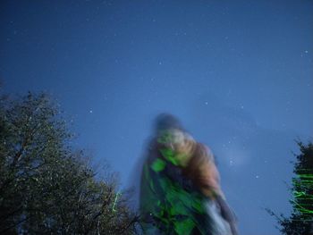 Low angle view of woman standing against blue sky