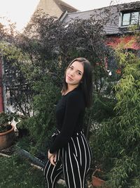 Portrait of smiling young woman standing against plants