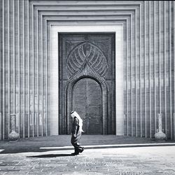 Side view of man walking against mosque
