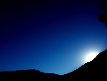 Low angle view of silhouette mountain against clear blue sky