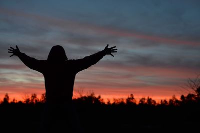 Silhouette woman against orange sky during sunset