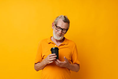 Young man using mobile phone against yellow background