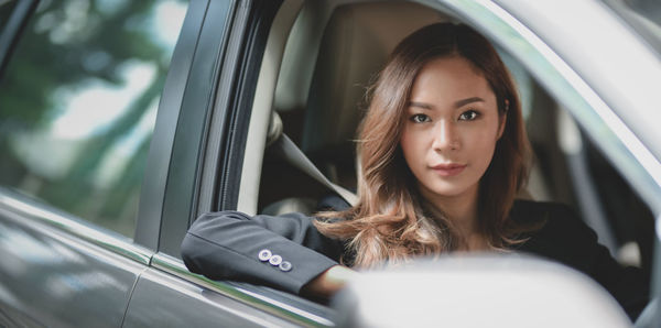 Portrait of woman sitting in car seen through window