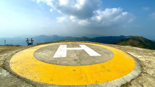 Arrow sign on road against sky