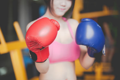 Midsection of woman wearing boxing glove while standing in ring