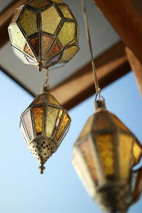 Low angle view of lamps hanging on roof against sky