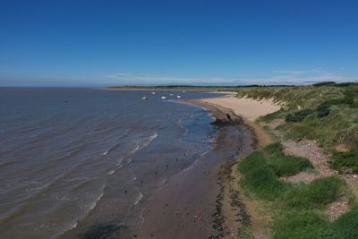 Scenic view of beach against clear blue sky