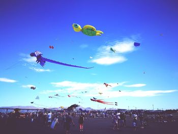 Low angle view of people flying against blue sky