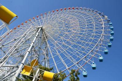 Low angle view of ferris wheel against clear blue sky