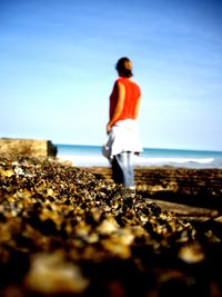 Rear view of woman standing on beach against clear sky