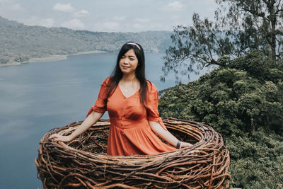 Portrait of smiling young woman standing against trees
