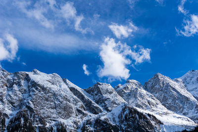 Low angle view of snowcapped mountains against blue sky