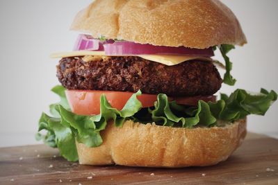 Close-up of burger on cutting board against white background