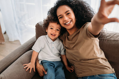 Portrait of smiling mother with son relaxing on sofa