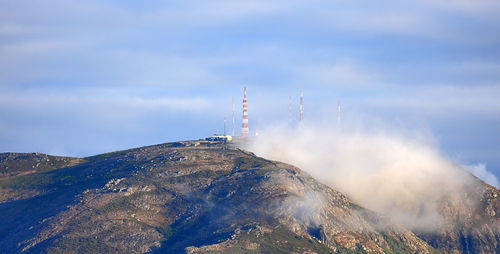 Smoke emitting from mountain against sky