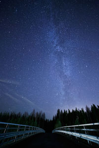 Footbridge and trees against star field at night