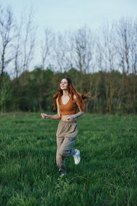 Full length of young woman playing with ball on grassy field