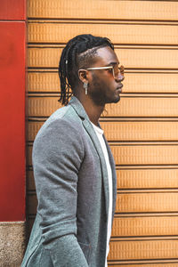 Man wearing sunglasses standing against wall