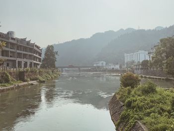 View of buildings by river against sky