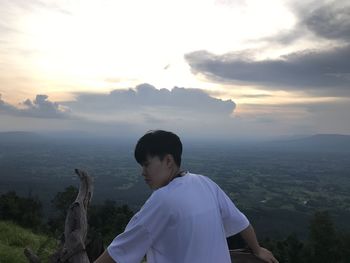 Rear view of man on mountain against sky during sunset