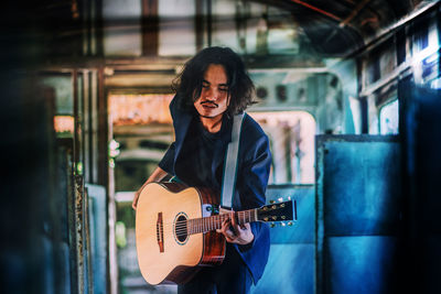 Young guitarist playing guitar in bus