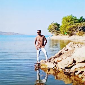 Young man standing in sea against sky