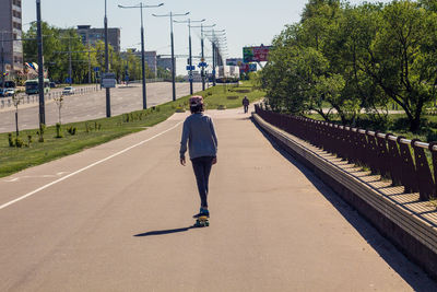Rear view of man walking on road in city