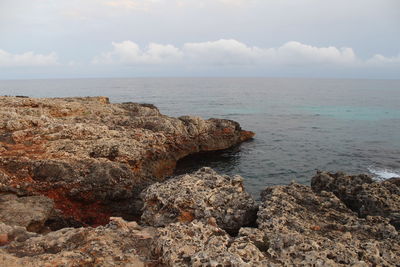 Scenic view of rocks on shore against sky