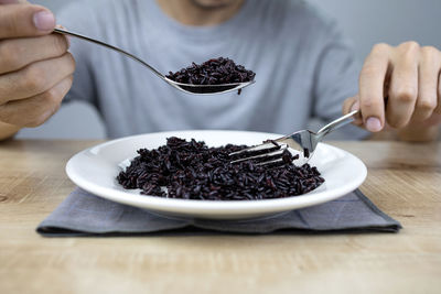 Midsection of person having breakfast on table