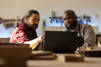 Portrait of man using digital tablet while sitting on table