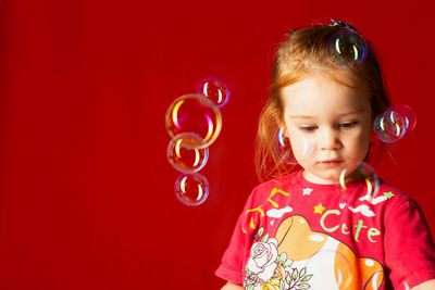 Portrait of cute girl blowing bubbles against yellow wall