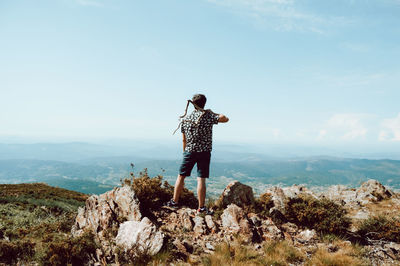 Rear view of man standing on rock against mountain