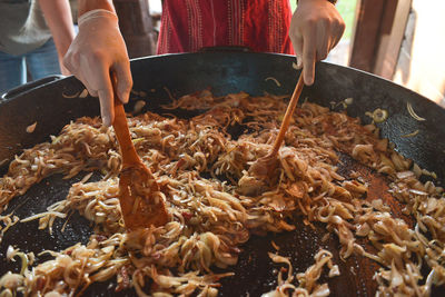 Midsection of person preparing food in cooking utensil