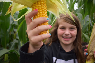 Portrait of smiling girl holding corns on field