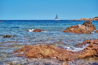 Sailboats sailing on sea against clear blue sky