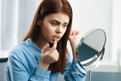 Young woman examining lips