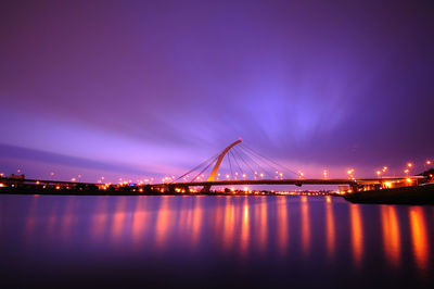 View of suspension bridge over river at night