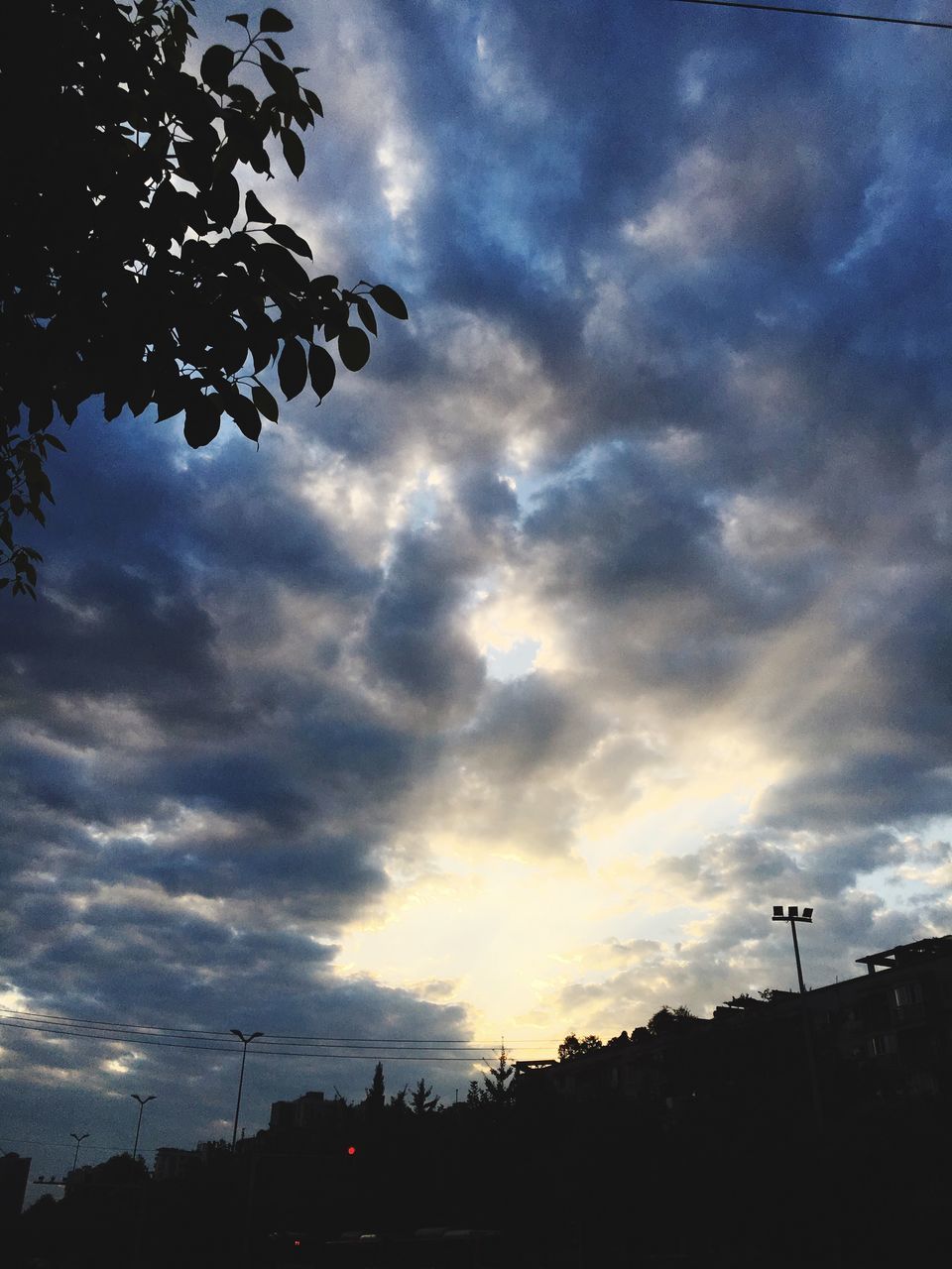 sky, cloud - sky, low angle view, cloudy, tree, street light, sunset, cloud, nature, weather, beauty in nature, tranquility, overcast, outdoors, dramatic sky, no people, scenics, tranquil scene, dark, growth, landscape