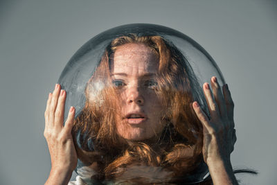 Portrait of scary young woman wearing glass helmet in head against gray background