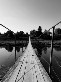 Footbridge over river against clear sky