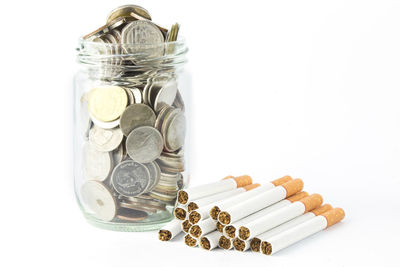 Close-up of coins in jar against white background