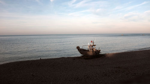 Boat in sea against sky during sunset