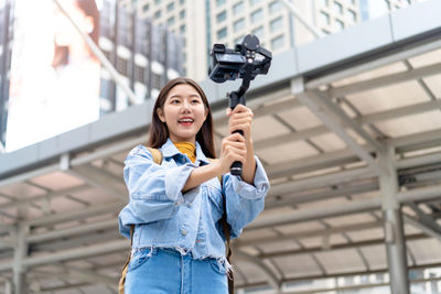 Portrait of smiling young woman holding camera