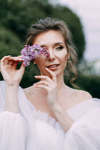 Beautiful bride in a wedding dress walks in a blooming apple-tree park in spring