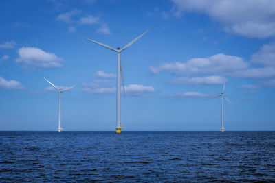 Wind turbines in sea against sky