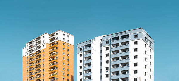 Low angle view of apartment building against clear blue sky