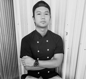 Portrait of young man standing against door at home