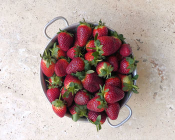 High angle view of strawberries in bowl on stone table 